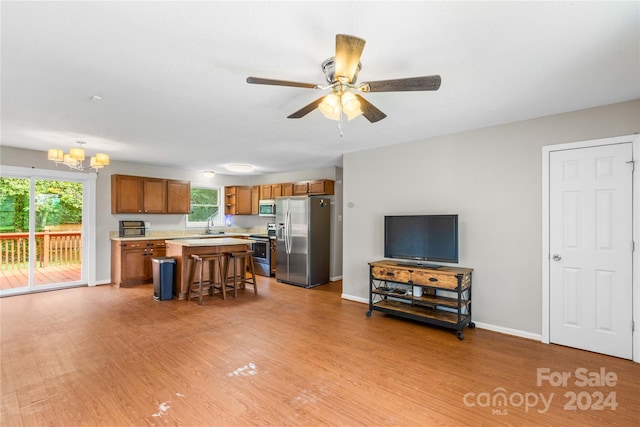 living room featuring light hardwood / wood-style flooring, sink, and ceiling fan with notable chandelier