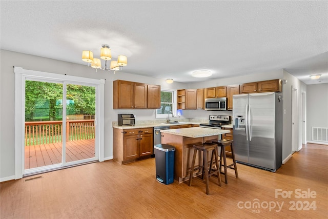 kitchen featuring a kitchen island, a kitchen breakfast bar, appliances with stainless steel finishes, and light hardwood / wood-style floors