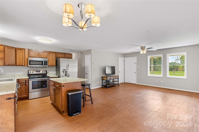 kitchen featuring light wood-type flooring, ceiling fan with notable chandelier, a center island, sink, and appliances with stainless steel finishes