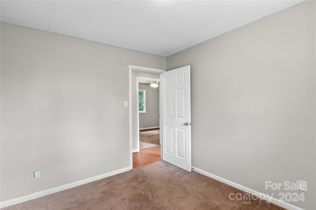 empty room featuring a textured ceiling, ceiling fan, and carpet floors