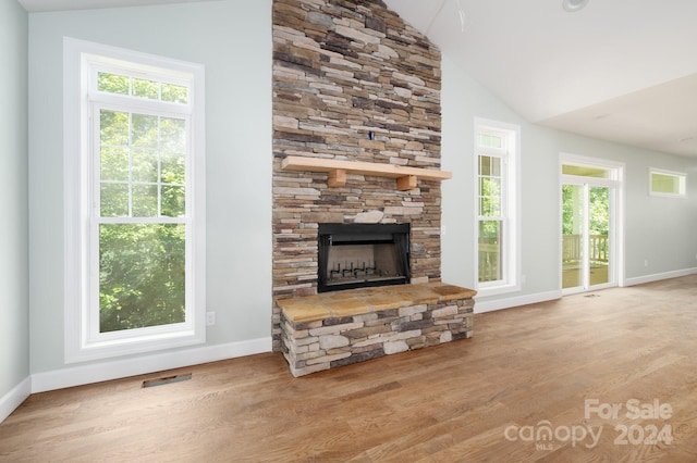 living room featuring a wealth of natural light, lofted ceiling, and light hardwood / wood-style flooring