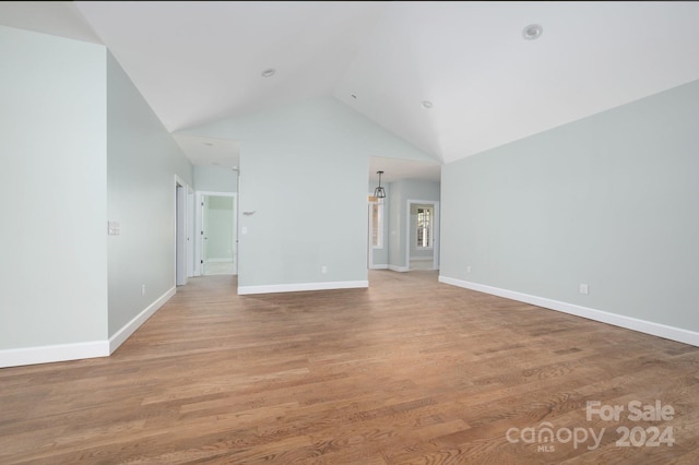 unfurnished living room featuring lofted ceiling and wood-type flooring