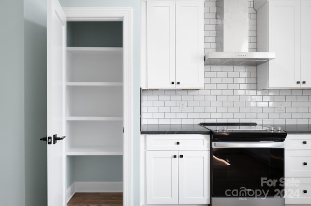 kitchen with tasteful backsplash, white cabinetry, wall chimney exhaust hood, stainless steel electric range, and dark wood-type flooring