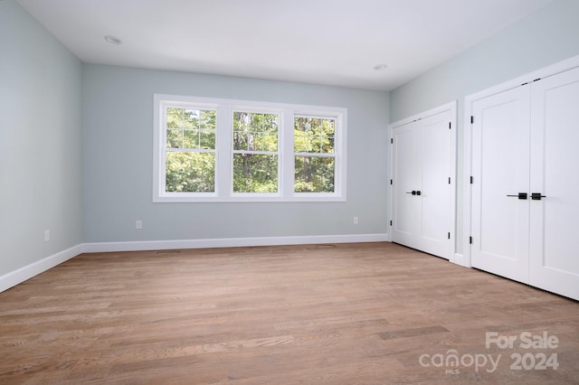 unfurnished bedroom with two closets and light hardwood / wood-style floors