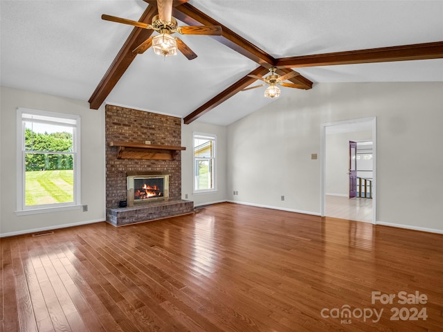 unfurnished living room featuring a fireplace, lofted ceiling with beams, wood-type flooring, and ceiling fan