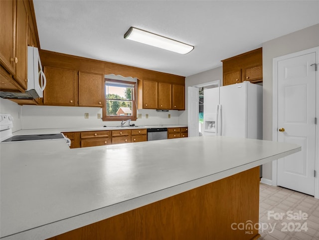 kitchen with white appliances, kitchen peninsula, and sink