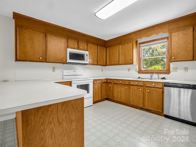 kitchen with kitchen peninsula, sink, and white appliances