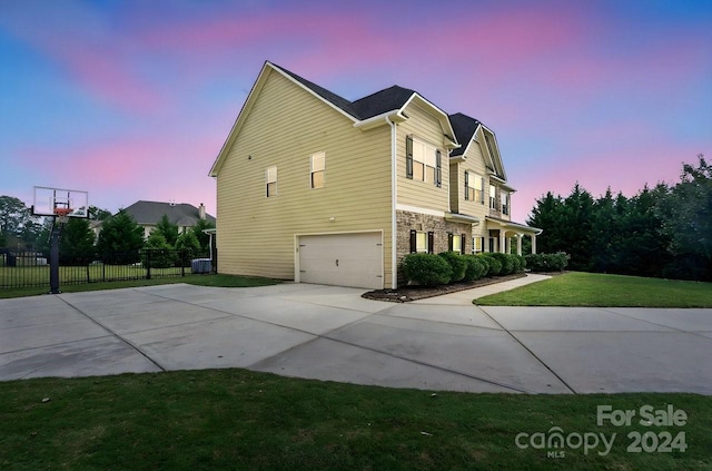 property exterior at dusk with a garage and a lawn