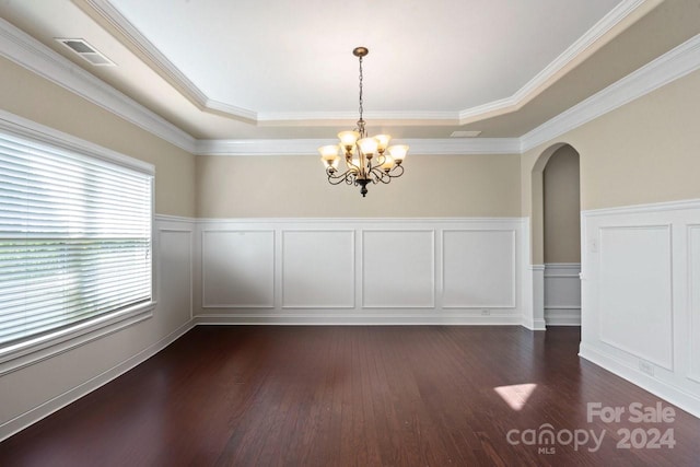 unfurnished dining area with a chandelier, a raised ceiling, dark wood-type flooring, and crown molding