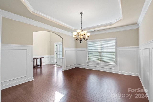 empty room with ornamental molding, a raised ceiling, a chandelier, and dark hardwood / wood-style flooring