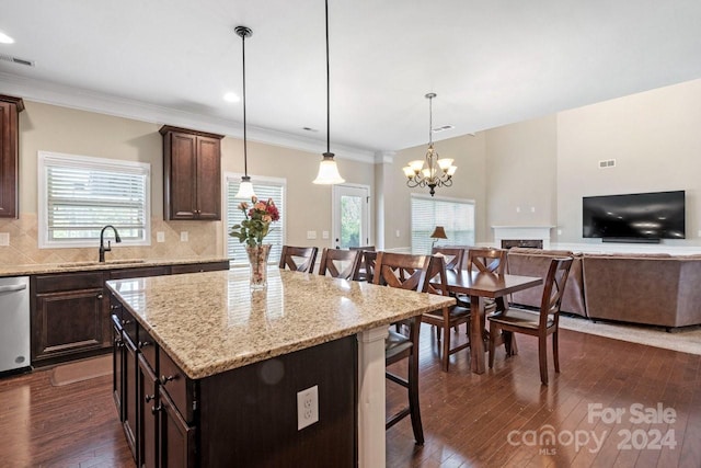 kitchen with decorative light fixtures, dark wood-type flooring, a kitchen bar, and a kitchen island