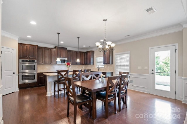 dining area with ornamental molding, a notable chandelier, and dark wood-type flooring