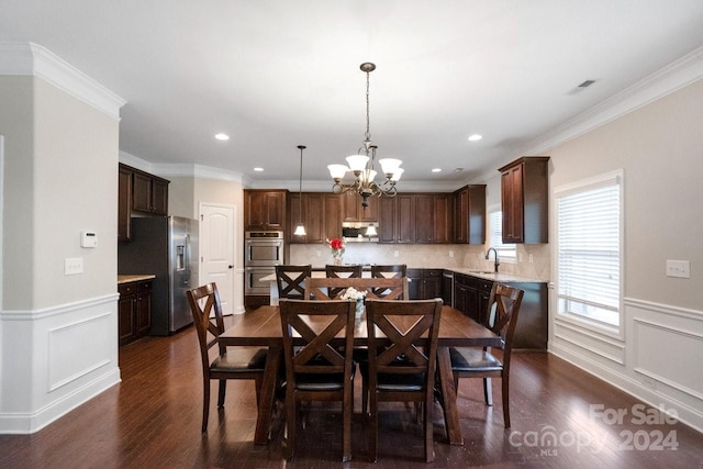 dining area with an inviting chandelier, ornamental molding, sink, and dark wood-type flooring