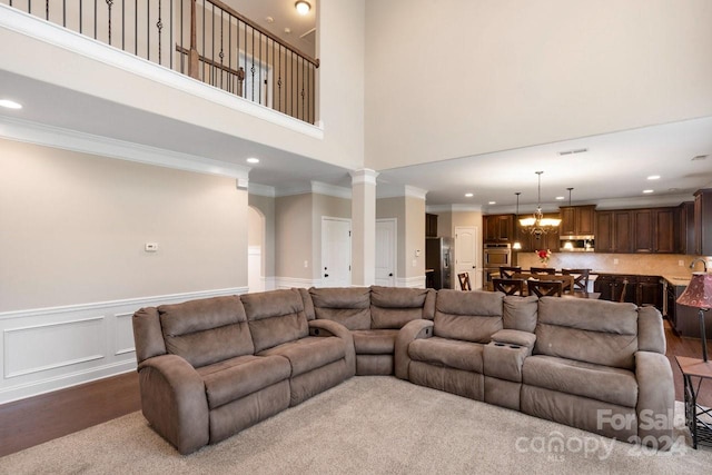 living room featuring ornate columns, ornamental molding, hardwood / wood-style floors, and a high ceiling