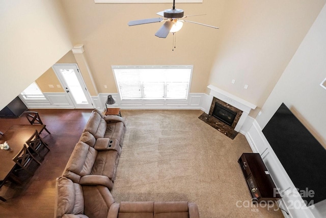 carpeted living room featuring ceiling fan and a towering ceiling