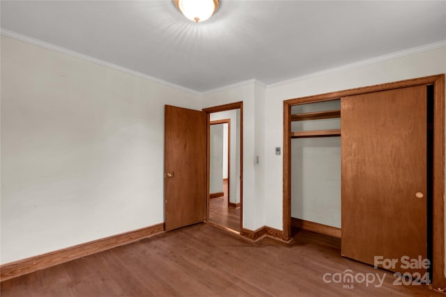 unfurnished bedroom featuring ornamental molding, a closet, and hardwood / wood-style flooring