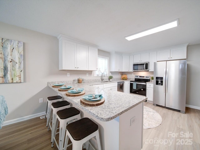 kitchen with white cabinets, kitchen peninsula, sink, and appliances with stainless steel finishes