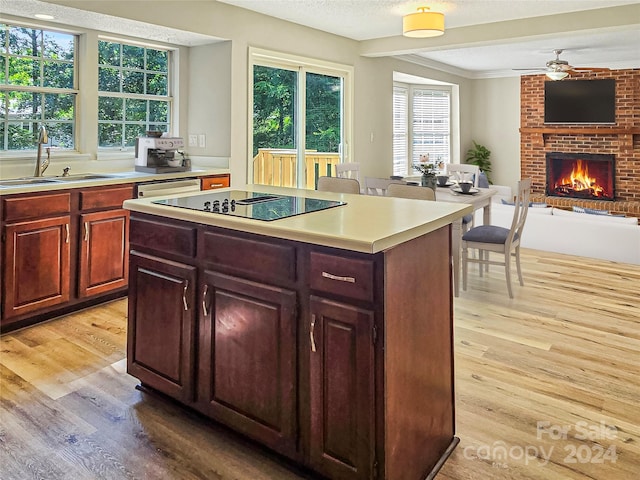 kitchen featuring a brick fireplace, light wood-type flooring, sink, brick wall, and a kitchen island