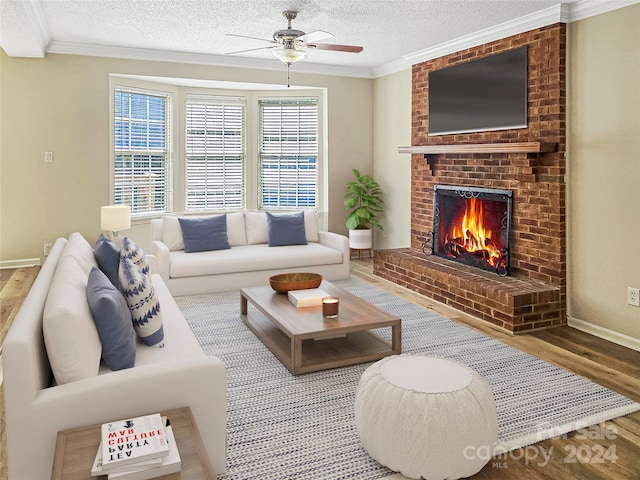 living room with a textured ceiling, plenty of natural light, hardwood / wood-style floors, and a brick fireplace