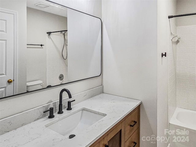 full bathroom featuring tiled shower / bath combo, vanity, and toilet