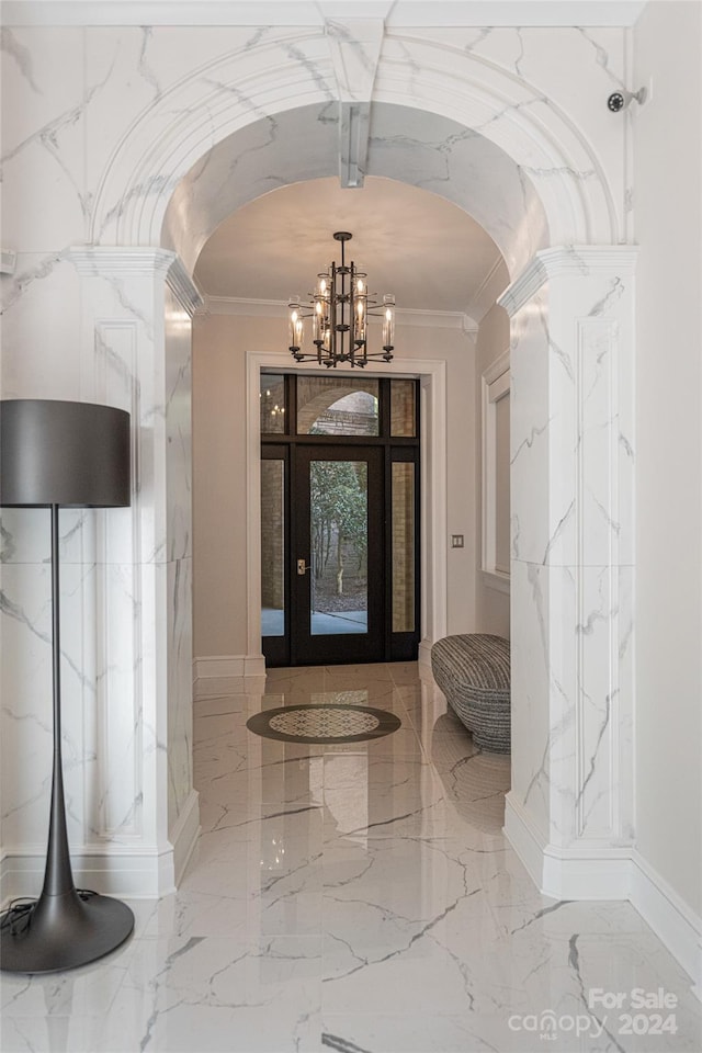 entrance foyer with ornate columns, a chandelier, and ornamental molding