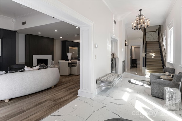 interior space with a fireplace, light wood-type flooring, ornamental molding, and a notable chandelier