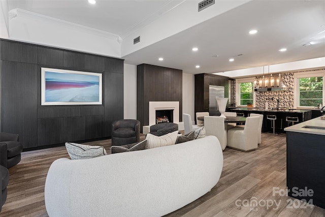 living room featuring crown molding, hardwood / wood-style flooring, a fireplace, and an inviting chandelier