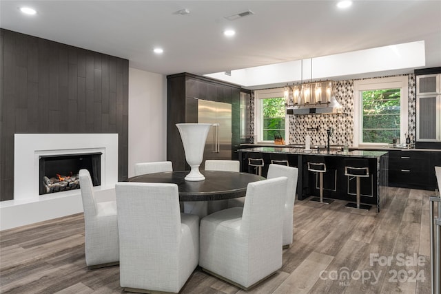 dining room with bar area, a fireplace, a notable chandelier, and light hardwood / wood-style flooring