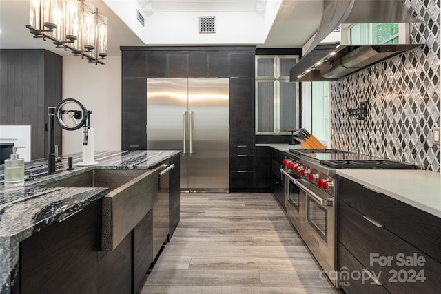 kitchen featuring light hardwood / wood-style flooring, range hood, stone counters, and high quality appliances