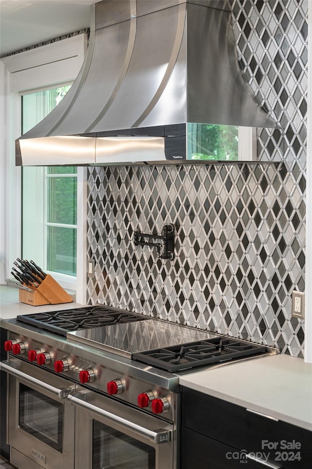 kitchen with ventilation hood, backsplash, and range with two ovens