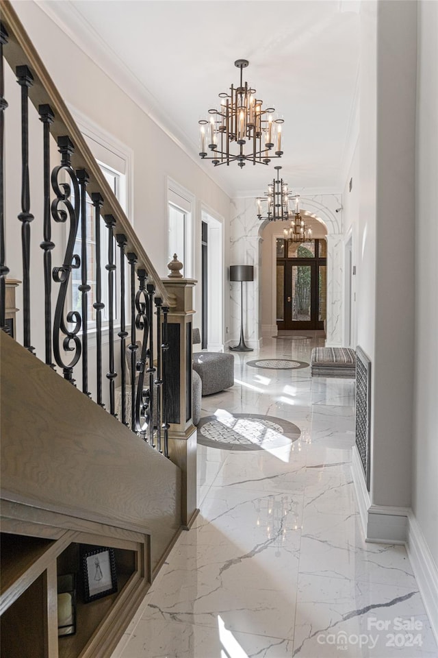 entryway with crown molding and a chandelier