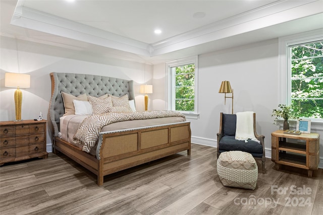 bedroom with crown molding, a raised ceiling, and hardwood / wood-style flooring