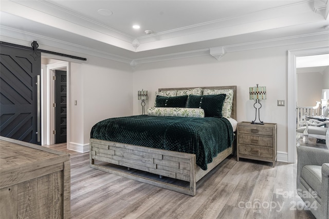 bedroom with a barn door, light hardwood / wood-style floors, and crown molding