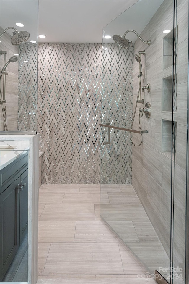 bathroom featuring vanity, a tile shower, and tile patterned floors