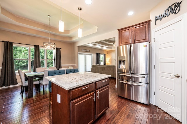 kitchen featuring a raised ceiling, hanging light fixtures, a kitchen island, dark hardwood / wood-style floors, and stainless steel refrigerator with ice dispenser