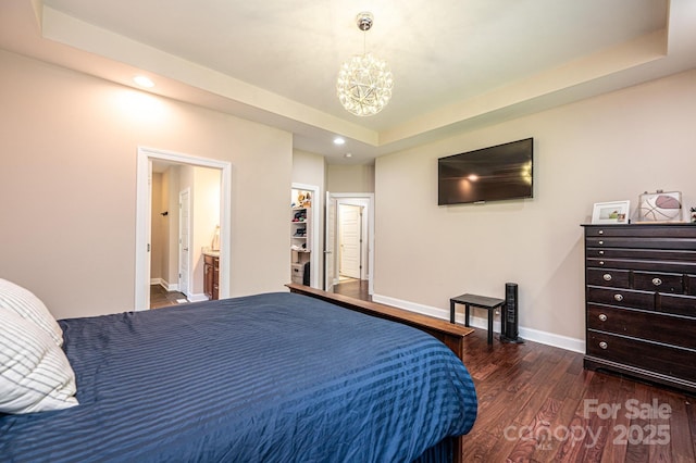 bedroom featuring a spacious closet, ensuite bathroom, a closet, a tray ceiling, and dark hardwood / wood-style flooring