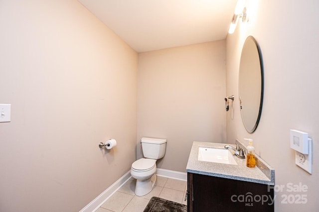 bathroom with toilet, vanity, and tile patterned floors