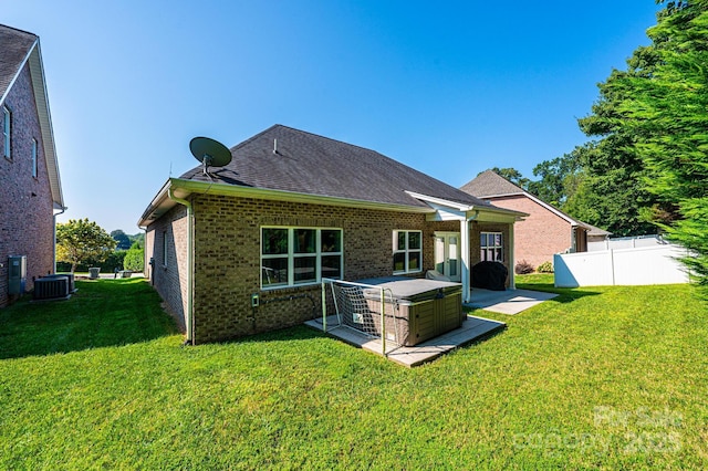 back of property featuring a hot tub, a patio, a yard, and central AC unit