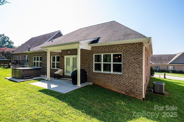 rear view of property featuring central air condition unit, a patio, a lawn, french doors, and a hot tub