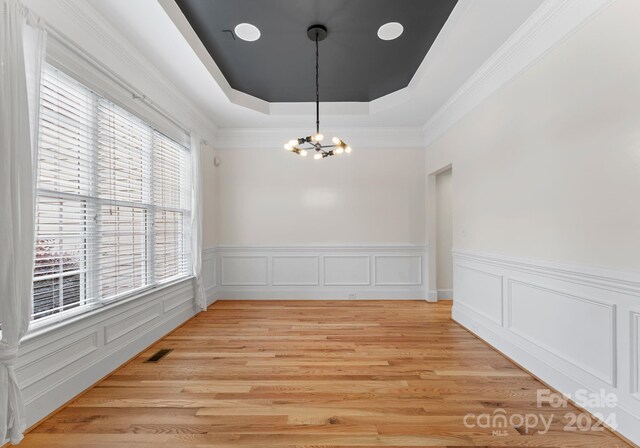 unfurnished dining area featuring a healthy amount of sunlight, light hardwood / wood-style floors, and a chandelier