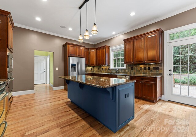 kitchen featuring dark stone counters, a kitchen island, appliances with stainless steel finishes, and light hardwood / wood-style flooring