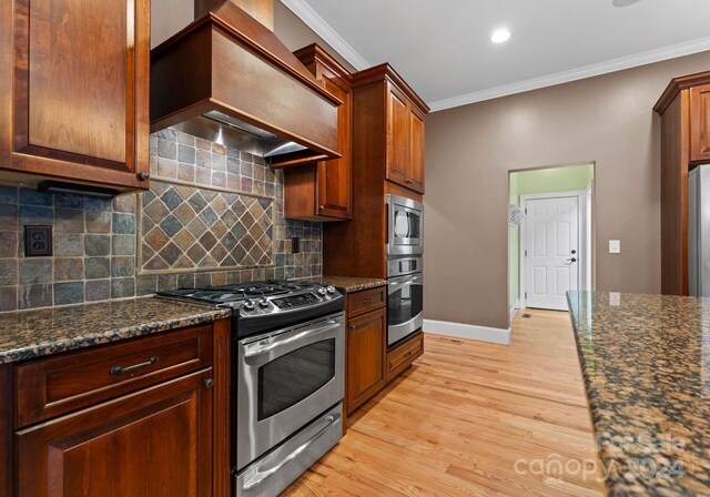 kitchen with custom range hood, stainless steel appliances, light hardwood / wood-style flooring, and ornamental molding