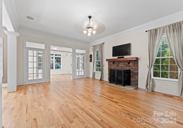 unfurnished living room with a fireplace, light wood-type flooring, ceiling fan, and crown molding