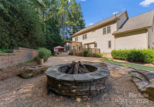 back of house with a wooden deck, an outdoor fire pit, and a patio