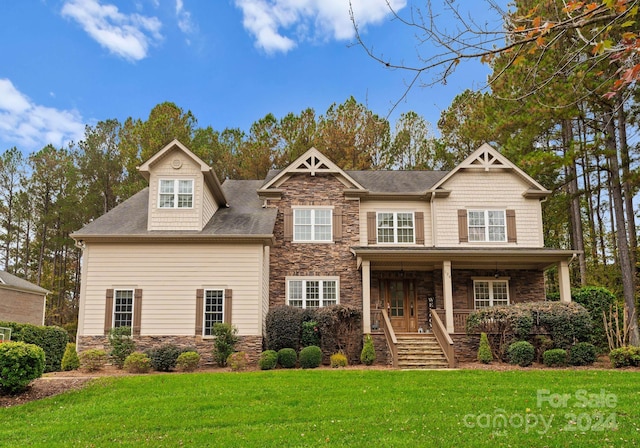 craftsman-style home with a front yard, covered porch, and stone siding