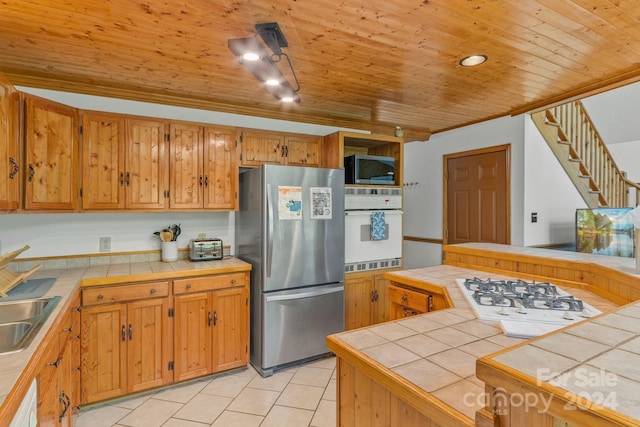 kitchen with tile countertops, light tile patterned floors, stainless steel appliances, kitchen peninsula, and wooden ceiling