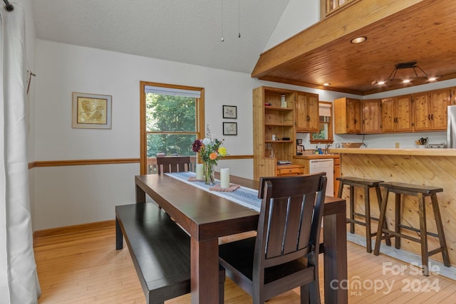 dining area with a textured ceiling and light hardwood / wood-style floors