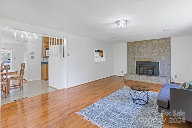 living room featuring a fireplace, an inviting chandelier, tile walls, wood-type flooring, and a textured ceiling