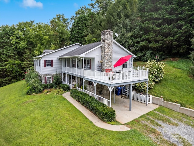 view of front of house featuring a chimney, driveway, stone siding, a front lawn, and a deck