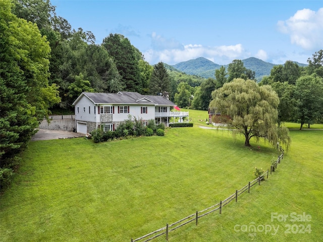 view of yard with a mountain view, driveway, fence, and an attached garage